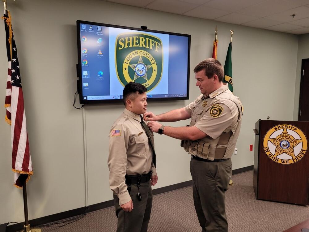 Sheriff Massey pinning badge on Sergeant Moua